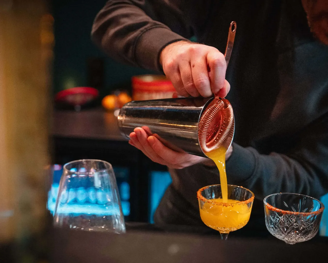 A cocktail being poured behind the bar